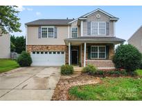 Charming two-story home featuring a stone facade, attached garage, well-manicured lawn, and welcoming front porch at 1911 Savannah Hills Dr, Matthews, NC 28105