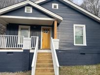 Charming exterior showcasing a blue home with a welcoming yellow door and wooden steps at 216 N Vance St, Gastonia, NC 28052