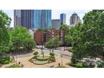 Brick building with trees and a fountain in front of skyscrapers in an urban setting at 224 N Poplar St # 24, Charlotte, NC 28202