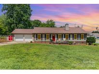 Charming single-story home with a well-manicured lawn, a red front door and a two-car garage at 2401 Hoffman St, Gastonia, NC 28054