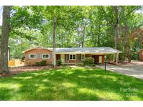 Charming brick home with a well-maintained lawn, mature trees, and covered carport at 403 Cherrywood Ln, Albemarle, NC 28001