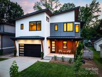 Stunning modern home with a two-car garage and a welcoming front porch with two chairs at 4108 Commonwealth Ave, Charlotte, NC 28205