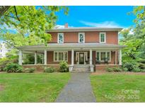 Charming two-story brick home featuring a welcoming front porch with classic columns and a beautifully landscaped yard at 634 E Center Ave, Mooresville, NC 28115