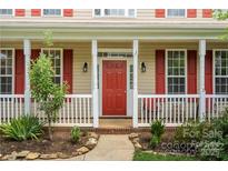Charming front porch with red door, white railing and columns, and manicured landscaping at 6614 Truman St, Indian Trail, NC 28079