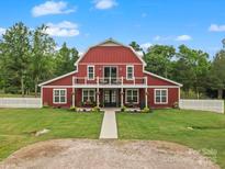 Striking barn-style home featuring a red exterior, white trim, covered porch, and manicured lawn at 925 Hamilton Rd, Chester, SC 29706
