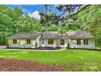 Charming single-story home featuring lush green lawn, mature trees, and a manicured landscape at 9520 Squirrel Hollow Ln, Charlotte, NC 28270
