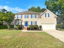 Charming two-story home with a manicured lawn, blue shutters, and a bright blue front door at 10319 Willingham Rd, Huntersville, NC 28078