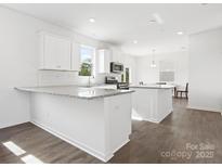 Bright kitchen featuring white cabinets, granite countertops, stainless steel appliances, and an island with a breakfast bar at 1433 Harleston St, Indian Trail, NC 28079