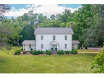 Charming two-story white home with lush green lawn and mature trees, creating a serene and inviting setting at 1567 Jennings Rd, Statesville, NC 28625