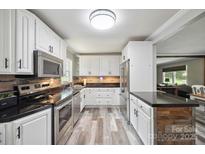Bright kitchen featuring white cabinets, stainless steel appliances, and modern countertops and backsplash at 327 Holly Dr, Mount Holly, NC 28120