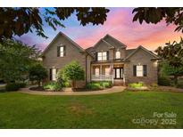 Charming brick home featuring manicured landscaping, inviting front porch, and a circular driveway at 389 Ponderosa Cir, Mooresville, NC 28117
