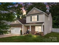Charming two-story home featuring stone accents, a cozy front porch, and well-manicured lawn at 413 Wheat Field Dr, Mount Holly, NC 28120