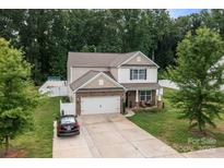 Two-story home with stone facade, two-car garage, and a well-maintained lawn and driveway at 413 Wheat Field Dr, Mount Holly, NC 28120