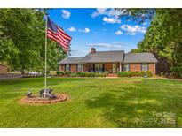 Charming brick home with well-manicured lawn, mature trees, and inviting front porch at 648 Odell School Rd, Concord, NC 28027