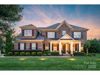 Charming two-story brick home featuring a welcoming front porch and manicured landscaping at 8301 Caesars Head Dr, Waxhaw, NC 28173