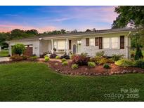 Charming brick home featuring a meticulously landscaped front yard and a welcoming front porch at 9135 Stokes Ferry Rd, Salisbury, NC 28146