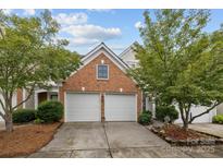 Home with a two-car garage and brick exterior surrounded by lush green trees at 10207 Garmoyle St, Charlotte, NC 28277