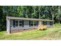 Charming ranch-style home with gray siding, dark shutters, and a welcoming front porch amid a wooded setting at 110 Lambert Ln, Statesville, NC 28677