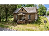 Charming brick home with gabled roof, front porch, and overgrown landscaping at 203 E College St, Star, NC 27356