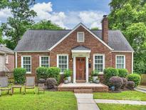 Charming brick home with a manicured lawn, lush landscaping, and inviting front porch with seating at 2222 Wilmore Dr, Charlotte, NC 28203