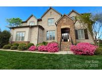 Charming brick home with manicured lawn and vibrant pink azaleas, creating a welcoming curb appeal at 324 Squash Harvest Ct, Matthews, NC 28104