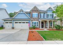 Charming two-story home with stone accents, inviting front porch, three car garage and manicured lawn at 3666 Jacinta Ct, Tega Cay, SC 29708