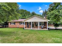 Charming one-story brick home featuring a covered front porch and a well-maintained lawn at 511 Apple Ln, Bessemer City, NC 28016