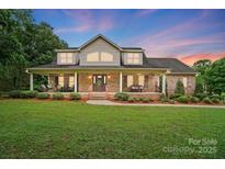 Charming two-story brick home with a large front porch, lush lawn, and beautiful landscaping at 803 Freeman Rd, Concord, NC 28025