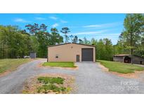 Exterior view of a metal building featuring a large garage door and gravel driveway at 10016 Morgan Mill Rd, Monroe, NC 28110
