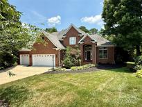 Beautiful brick home featuring a three-car garage and a meticulously manicured lawn and landscaping at 10317 Clubhouse View Ln, Mint Hill, NC 28227