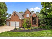 Charming brick home featuring a well-manicured lawn, mature trees, and a three car attached garage at 10317 Clubhouse View Ln, Mint Hill, NC 28227