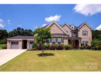 Beautiful brick home with a well-manicured lawn and mature landscaping, showcasing its curb appeal at 720 Cavesson Way, Monroe, NC 28110