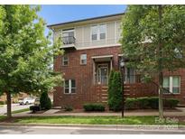 Charming brick townhome featuring multiple stories, a cozy balcony, and professionally landscaped front yard at 859 Academy St, Charlotte, NC 28205