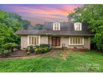 Charming one story brick home featuring three dormer windows and a landscaped front yard under a beautiful sunset sky at 9139 Robert Frost Ln, Charlotte, NC 28213