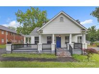 Charming white home featuring a cozy front porch with black railings and a bright blue front door at 111 E Church St, Stanley, NC 28164