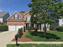 Charming two-story home with a brick and cedar facade, manicured lawn, mature tree, and a two-car garage at 1572 Edenton Nw St, Concord, NC 28027