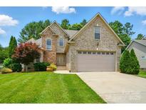 Charming two-story brick and stone home with a well-manicured lawn and attached two-car garage at 1705 Townsend Ln, Rock Hill, SC 29730