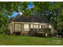 Expansive rear exterior showcasing a charming deck, screened-in porch, and well-manicured lawn at 171 Secretariat Dr, Mooresville, NC 28117