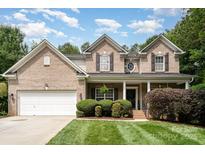 Charming brick home featuring a well-manicured lawn, attached two-car garage, and inviting front porch at 2504 Korbel Ct, Waxhaw, NC 28173