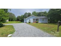 Charming blue home featuring a gravel driveway, manicured lawn, and mature trees at 2820 Bellhaven Cir, Charlotte, NC 28214