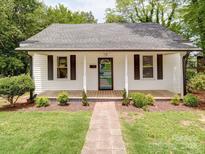 Charming home with a welcoming front porch, beautiful landscaping, and a brick walkway to the front door at 318 Chestnut Ave, Kannapolis, NC 28081
