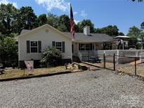 Charming home featuring a well-maintained yard, gravel driveway, and a welcoming front porch with an American flag at 533 Tuckers Grove Rd, Statesville, NC 28625
