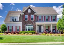 Charming two-story home with a combination of stone and siding and a well-manicured lawn at 8493 Twickenham Ter, Harrisburg, NC 28075