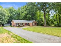 Charming brick home featuring a well-manicured lawn, mature trees, and long driveway at 8938 Glencroft Rd, Mint Hill, NC 28227