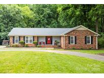 Charming single-story brick home with a red front door and a well-maintained lawn at 8938 Glencroft Rd, Mint Hill, NC 28227