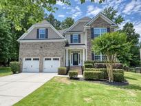 Beautiful two-story home boasts a two-car garage, stone accents, manicured lawn, and mature landscaping at 9507 Reid Hall Ln, Matthews, NC 28105