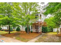 Charming two-story home with a covered porch and balcony, surrounded by mature trees and landscaping at 10407 Alvarado Way, Charlotte, NC 28277