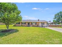 Charming single-story home with a well-maintained lawn, mature tree and American flag at 1204 N 12Th St, Bessemer City, NC 28016