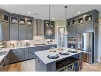 Modern kitchen features gray cabinets, stainless steel appliances, a spacious island and stylish pendant lighting at 18145 Sulton Ter, Huntersville, NC 28078