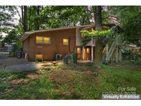 A cozy brick home featuring an elevated deck with backyard access, nestled among mature trees at 2255 Milton Rd, Charlotte, NC 28215